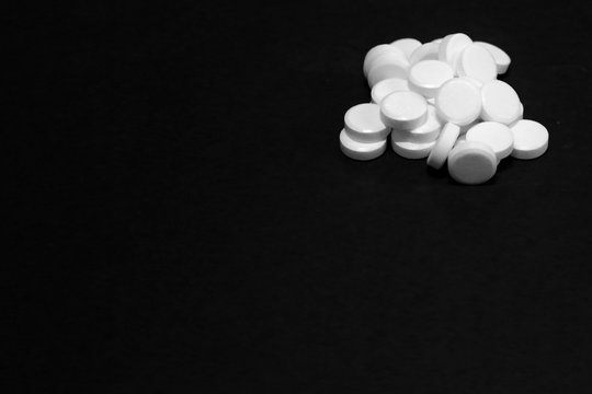 White pills, medicines, on a blach background © Marcin