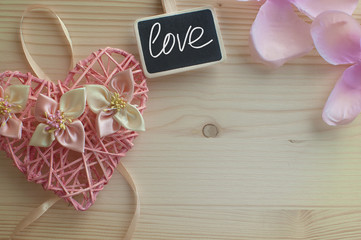 Wicker heart with flowers on wooden background. The concept gree