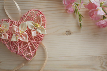 Wicker heart with flowers on wooden background. The concept gree