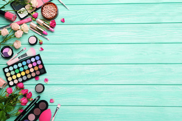 Different makeup cosmetics on mint wooden table