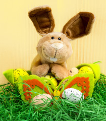 Osterhase sitzt hinter dem Körchen mit Ostereier, Ostern