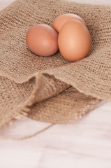 Eggs on burlap over wooden background