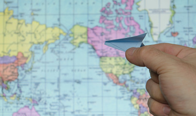 paper airplane on a background map of the world
