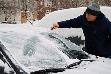 a man removes snow from car