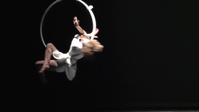 Mujer acróbata girando en el aro aéreo, chica bailarina actuando en el teatro