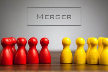 Merger concept with pawn figurines on table, grey background