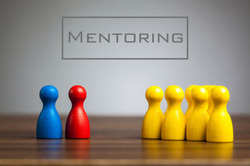 Mentoring concept with pawn figurines on table, grey background