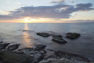 Sea coast in a long exposure shot at sunset, with blurred water