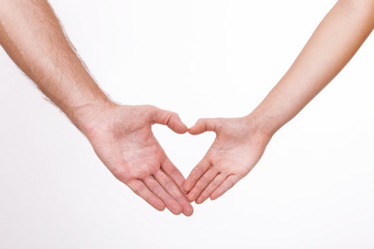 Young couple close to each other and smiling making heart shape made with their fingers isolated on white background.