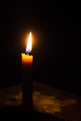 One light candle burning brightly in the black background