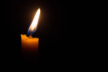 One light candle burning brightly in the black background