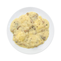 Ravioli in a cheese and mushroom sauce meal on a plate top view isolated on a white background.