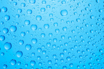 Water drops on blue glass surface texture.