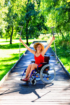 woman on a wheelchair rising her crutches