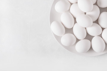 White eggs on a white plate on a white background. Eggs.  Easter photo concept. Copyspace