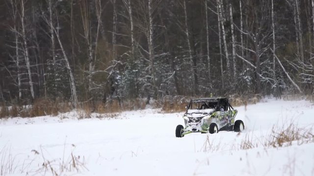 Winter racing side-by-side vehicles. Rally on the buggy on the snow on a winter day. Racing in the SXS class. Buggy, sports car on rally. Off Road Series racing. Slow motion.