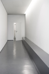 Current public interior corridor, Modern corridor, White modern hallway with doors, Open door in  hallway, Cast floor in minimalist interior - 135937136