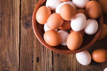White and brown eggs in a ceramic bowl on a wooden background. Rustic Style. Eggs.  Easter photo concept. Copyspace