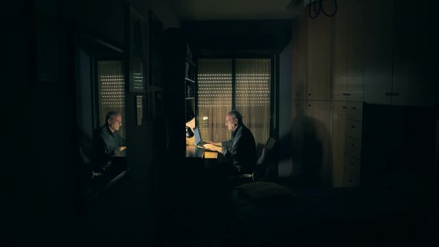 Old man chatting with computer in his bedroom