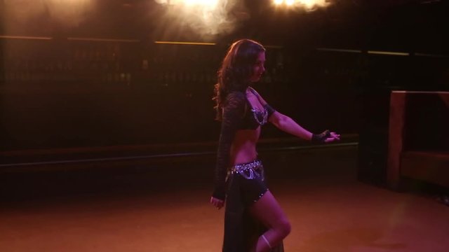 Female dancing belly dance in a nightclub. Smoke background