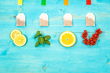 Flavored teabags fresh fruit top view on aquamarine wood table with copy space - Mint leaf lemon...