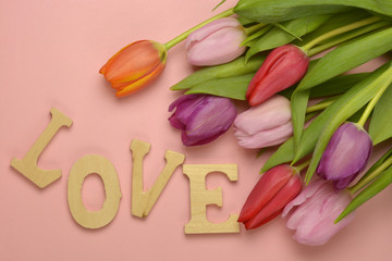Wooden grey empty copy space background with fresh colourful spring tulips. Orange, red,pink and purple tulips and Valentine love letters made of wood.