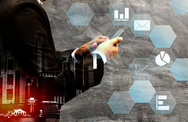 Double exposure - businessman using smartphone with city overlay
