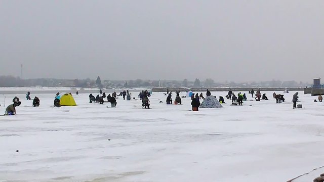 Timelapse winter human fishing on ice. Many fisherman on the frozen surface of the water to catch fish. Northern fishermen with tents fish extract drilling holes. Hobby hard men. Collective leisure. 