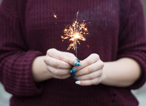 Sparkler lit in hands of a woman
