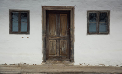 Fototapeta na wymiar Windows and door on an old houses wall