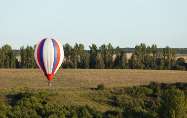 Obraz premium Balloons fly over the green fields, hills in summer