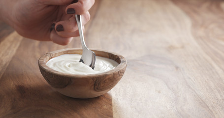 eating organic yogurt with spoon from wood bowl, 4k photo