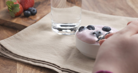 POV teen girl eating yogurt with blueberries, 4k photo