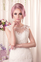 The beautiful woman posing in a wedding dress. Beautiful bride with makeup and hairstyle.