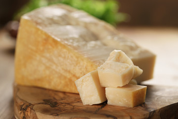 hard parmesan cheese cubes on olive cutting board, closeup photo