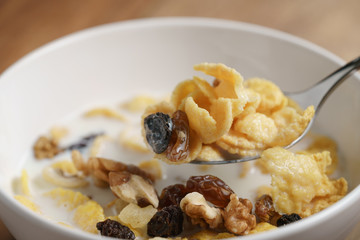 eating corn flakes with fruits and nuts in white bowl, healthy food