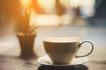 coffee with plant on the wood table at the sunrise