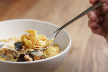 eating corn flakes with fruits and nuts in white bowl, healthy food