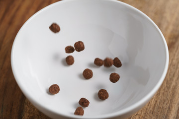 chocolate cereal balls in white bowl for breakfast, shallow focus
