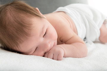 Sweet carefree newborn baby resting on warm white blanket