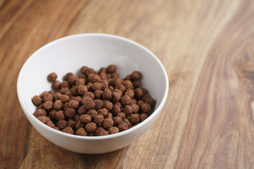 chocolate cereal balls in white bowl for breakfast, shallow focus
