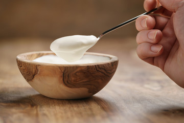 Fototapeta na wymiar eating organic yogurt with spoon from wood bowl, 4k photo