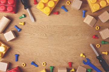Kids toys background. Colorful toy tools, construction blocks and cubes on wooden table. Top view. Flat lay. Copy space for text