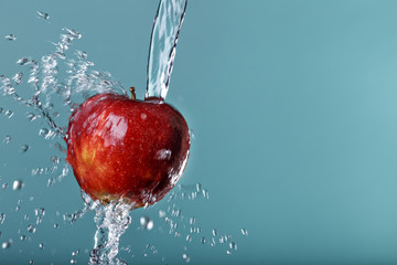 red apple in water drops on green background