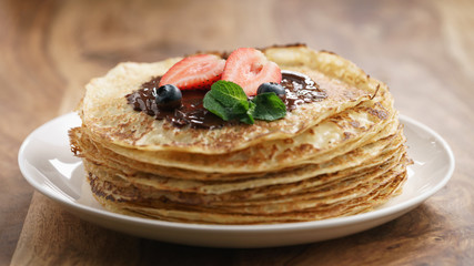 fresh blinis or crepes with melted dark chocolate and berries, shallow focus