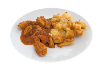 Plate with chicken chunks in barbecue sauce plus potatoes isolated on a white background.