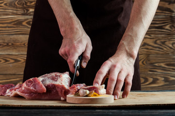 Butcher cutting pork meat on kitchen