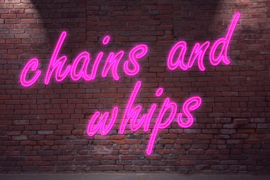 Leuchtreklame chains and whips an Ziegelsteinmauer
