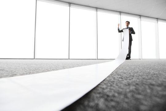 Office worker unrolling long sheet