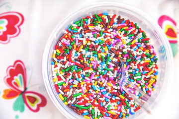 a bowl full of colorful candy sprinkles with a clear plastic spo